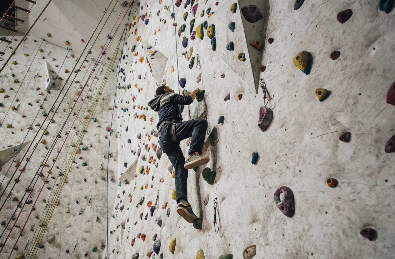 Low angle view of athletic man climbing on the wall in a gym.
